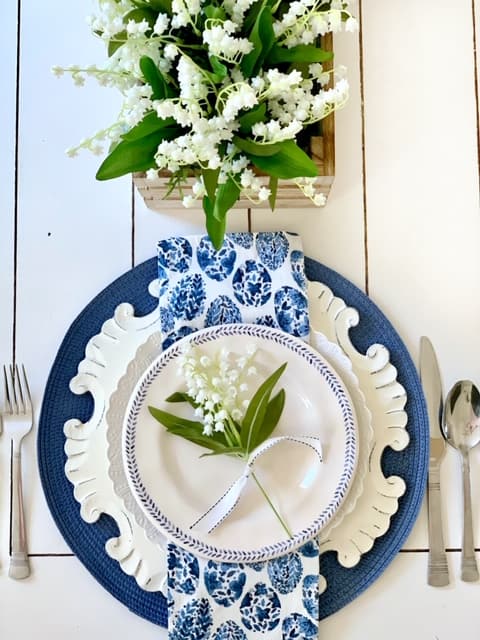 A blue and white easter table setting with a blue placemat blue and white dishes. 