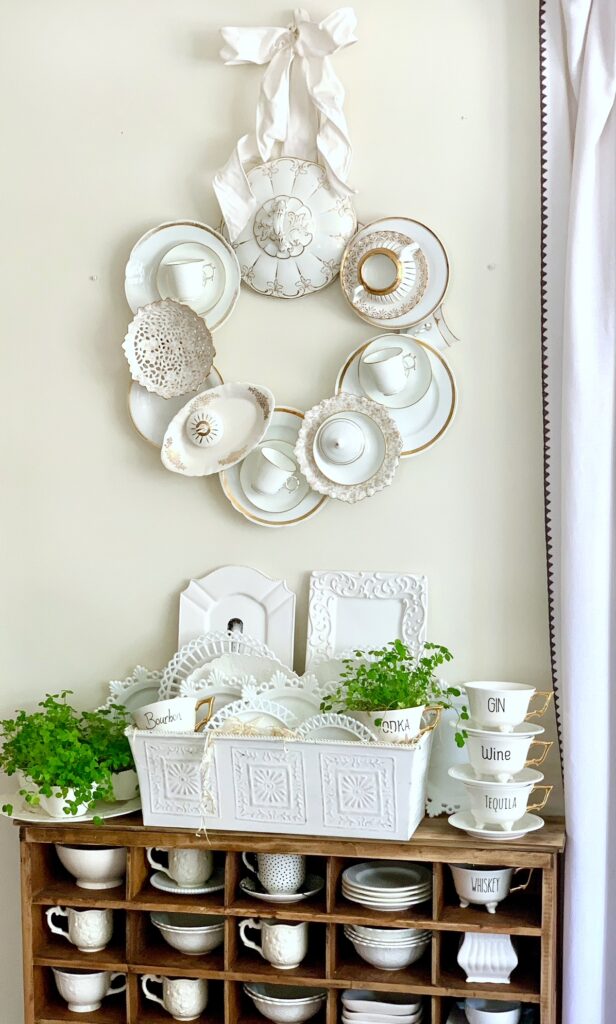 a wreath made from various china pieces. the china is layered on the wreath and is gold and white.