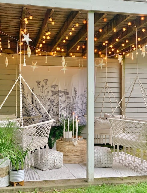 outdoor space with 4 hanging macrame hammock chairs, rugs, cafe lights and wicker decor.