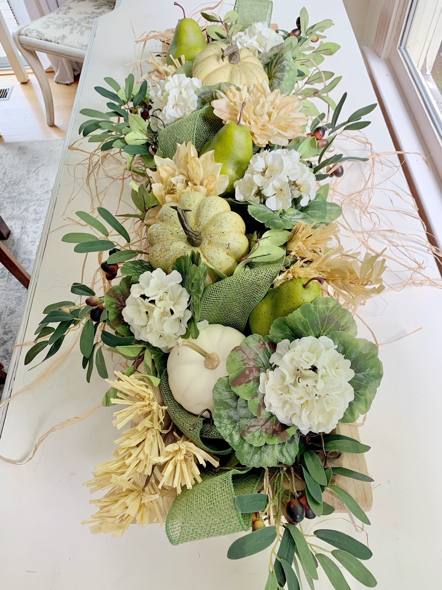 White pumpkins, geranium, pears, olive branches in a dough bowl.