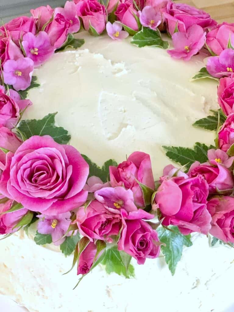 The finished cake with bright pink flowers and greens. 