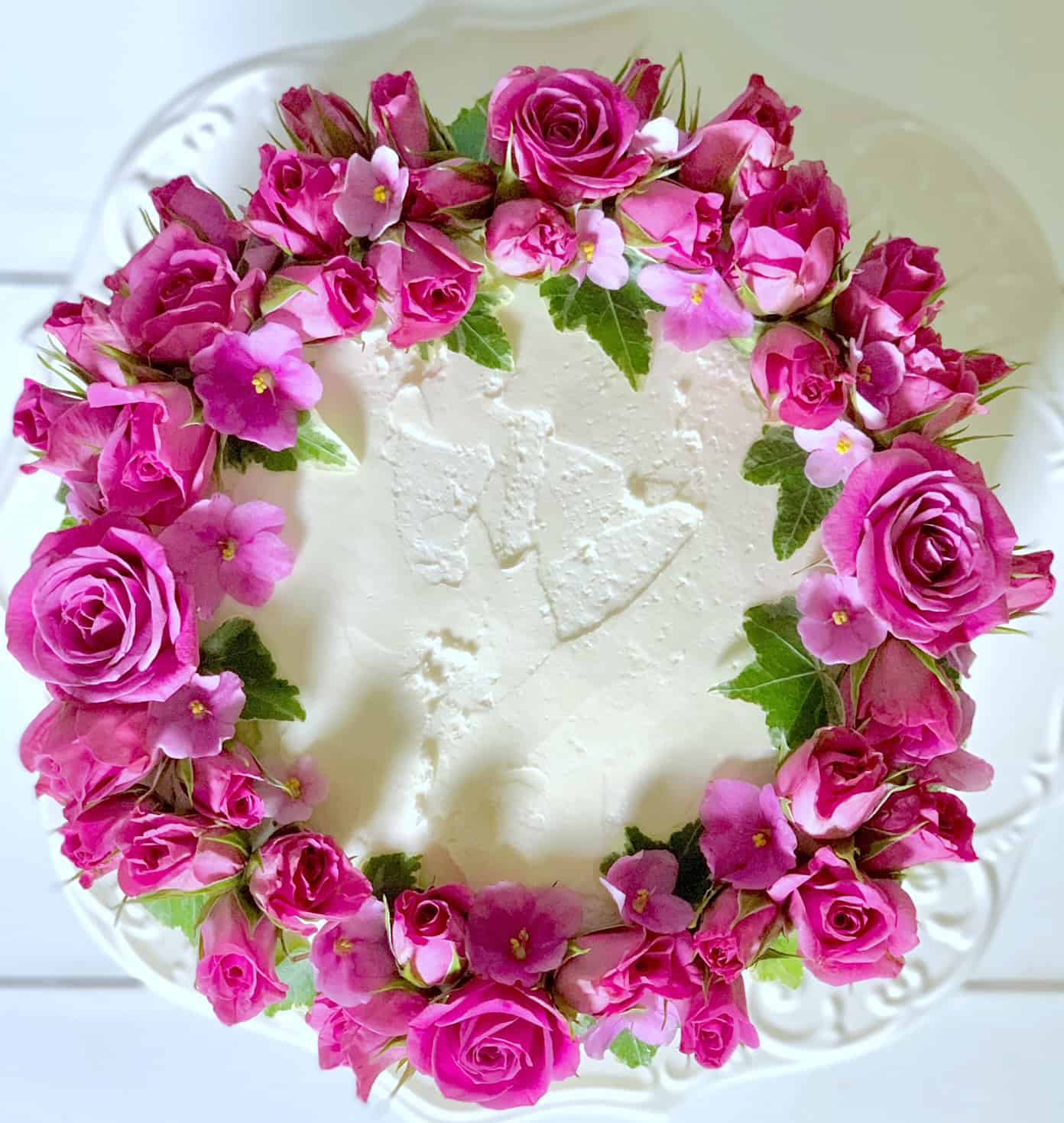 Top view of this cake. it has a ring of hot pink roses and violets around the top. 
