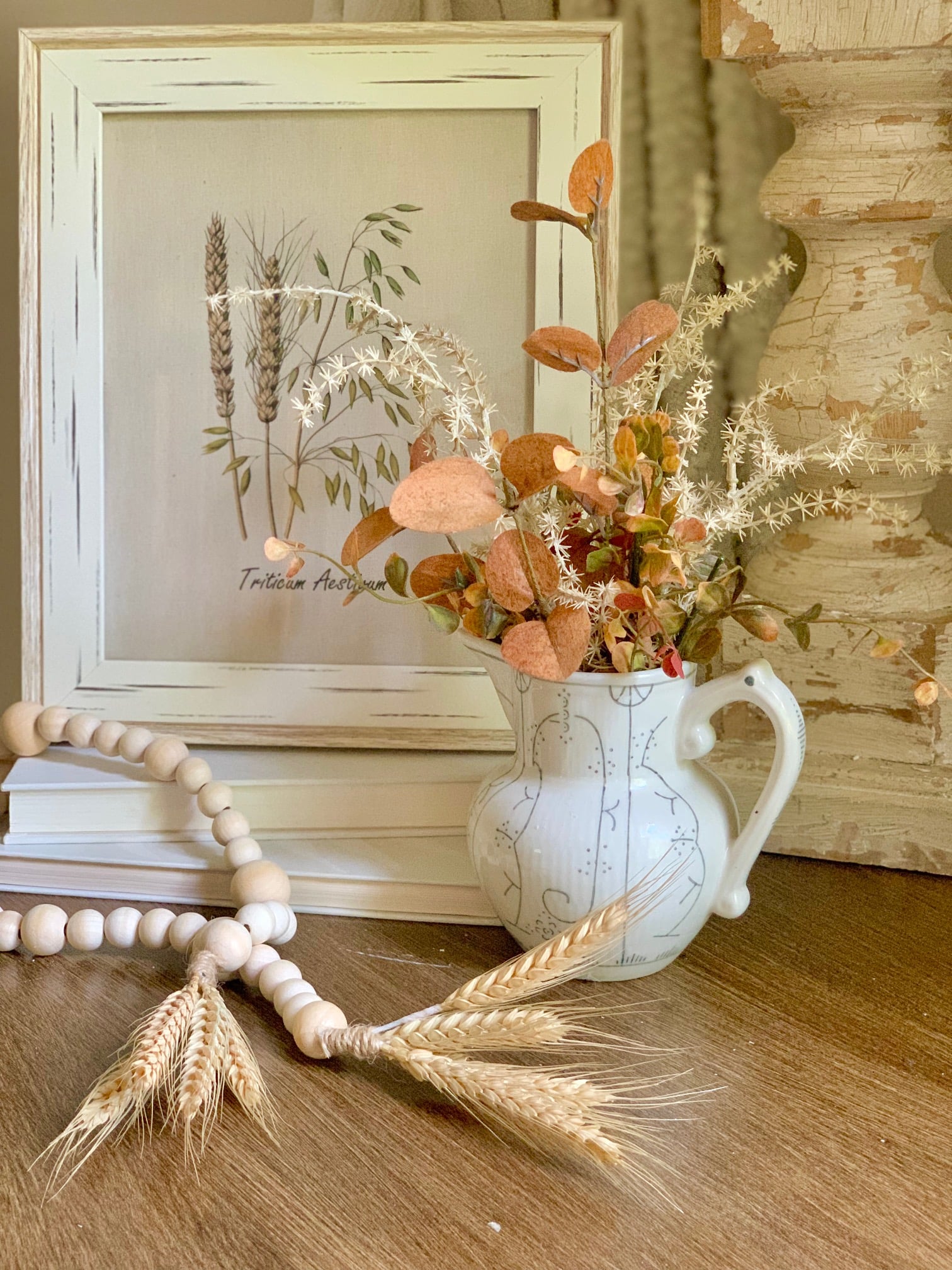 A small faux flower arrangement with a pair of decor beads with wheat as tassels.