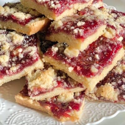 raspberry squares all stacked on a white plate