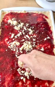 sprinkling crumb topping dough on jelly
