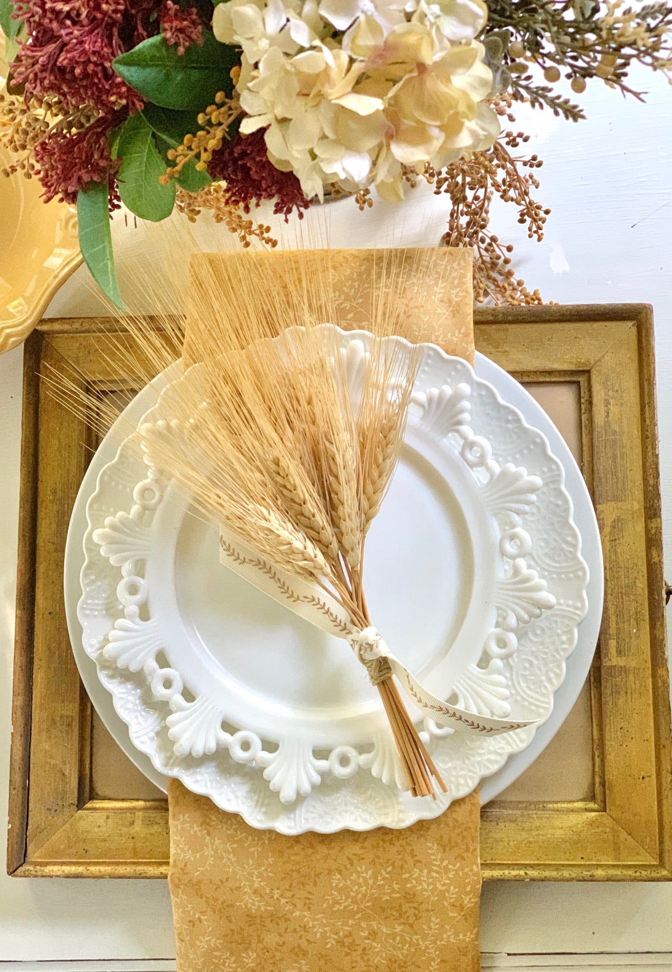 Table setting with white dishes and wheat bundles.