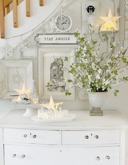 A white Vintage dresser with all white gallery wall with green and white arrangement.