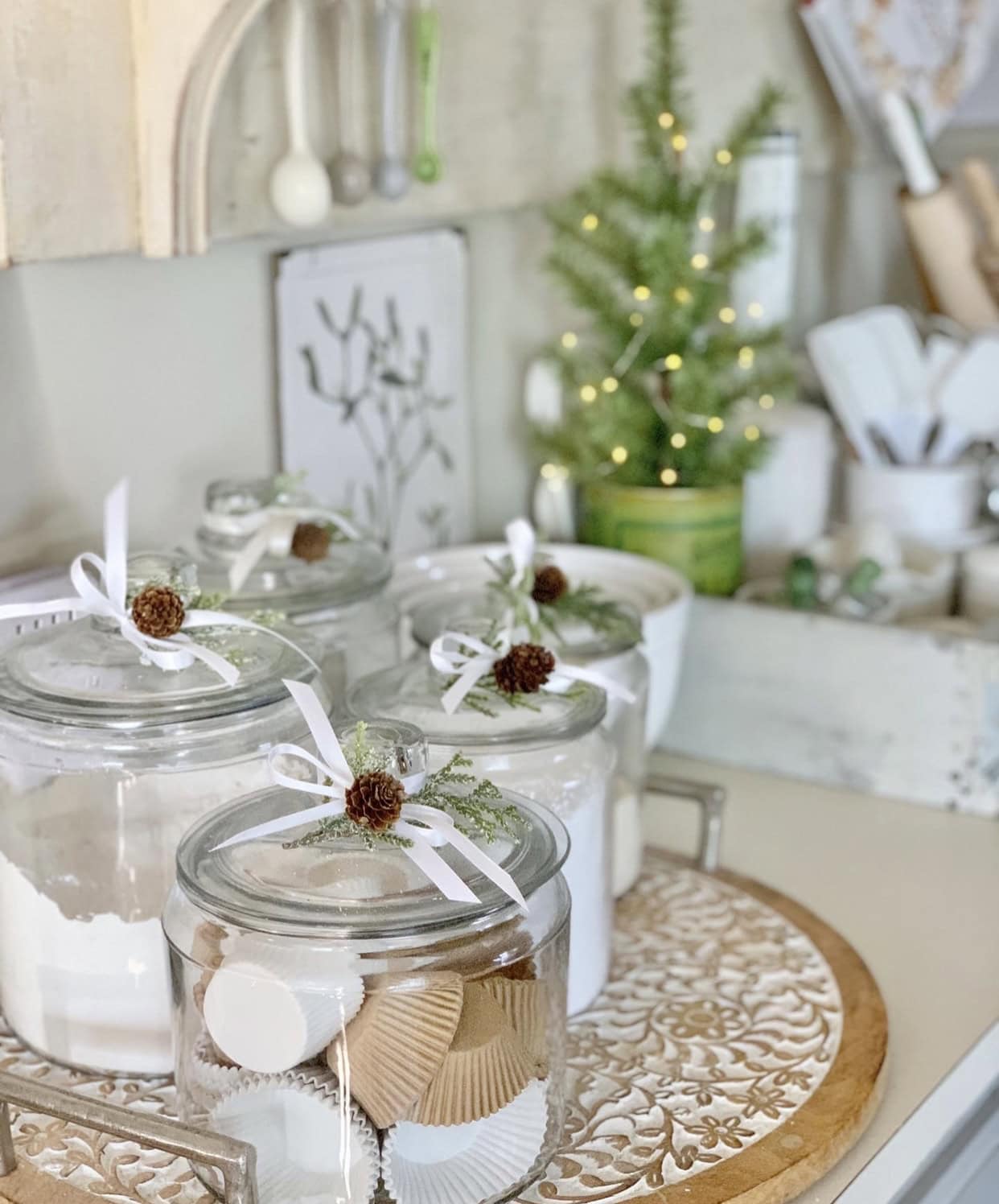 Glass canisters filled with dried goods decorated with bows and greens for Christmas. 
