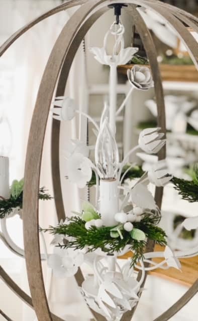 DIY embroidery hoop chandelier with christmas greens and berries around the lights. 