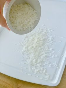 spreading coconut on a baking sheet