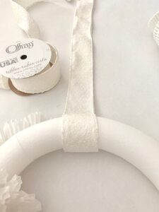 a ribbon wrapped arounf the top of a styrofoam wreath.
