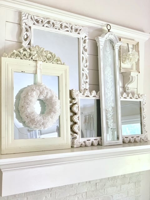 mantel with layers mirrors. one of the moirrors has the cupcake liner wreath hanging from it. 