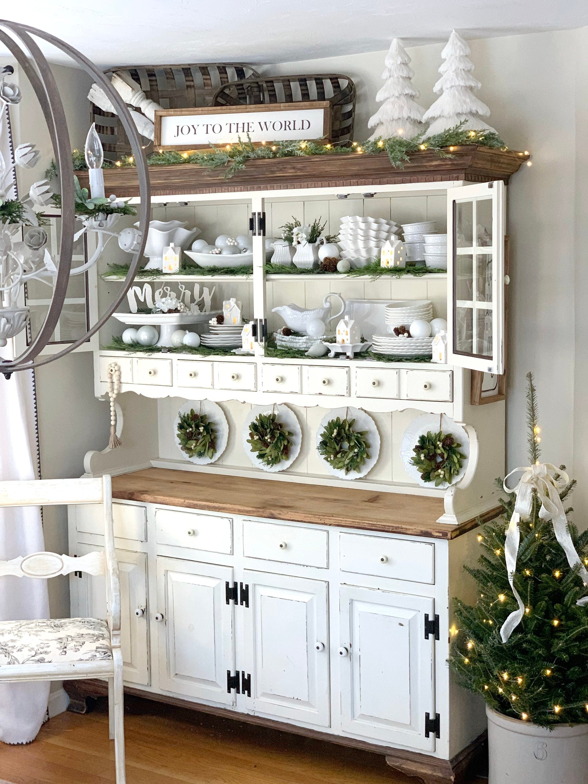 A Dining room hutch decorated for Christmas with green and white decor.