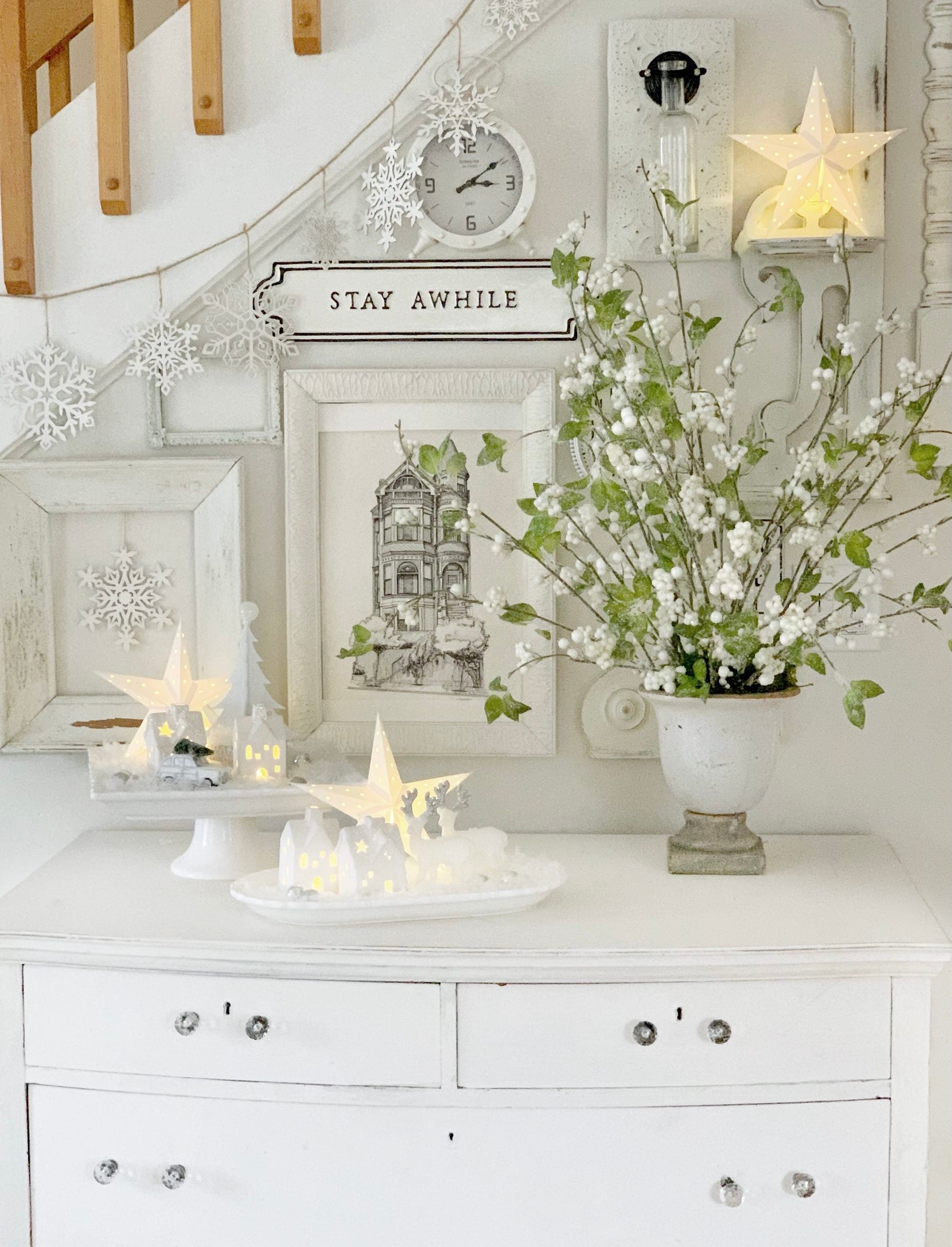 A white Vintage dresser with all white gallery wall with green and white arrangement.