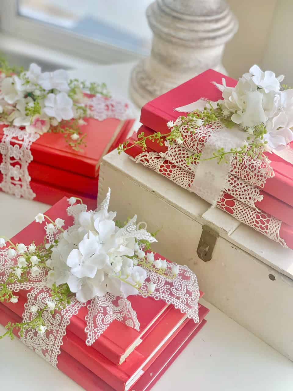 3 Valentines day diy book stacks with ribbon and faux flowers. 