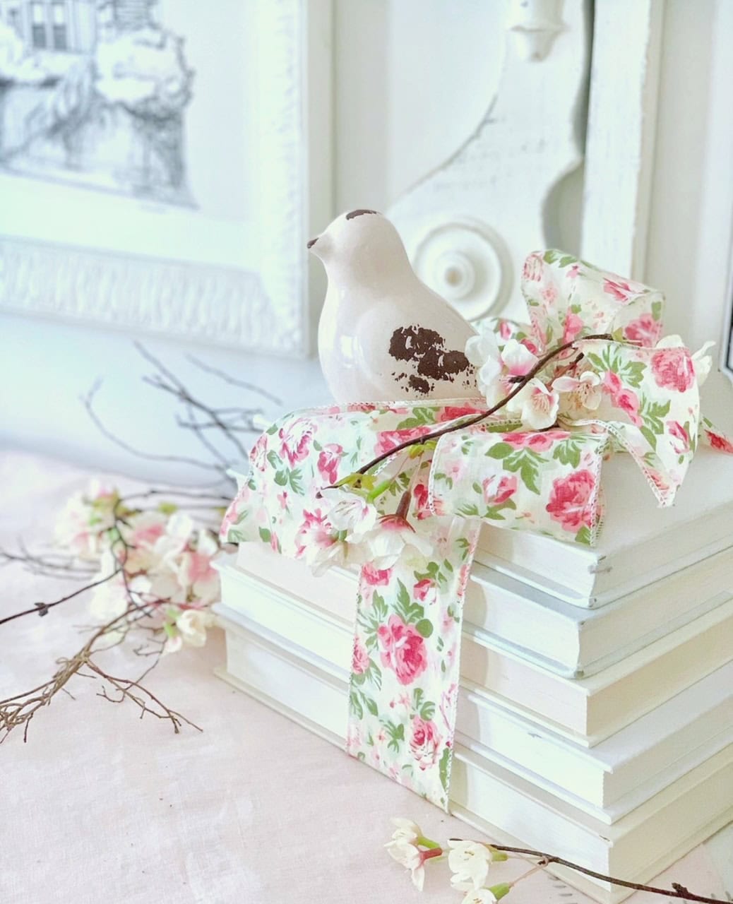 Stack of white books with a floral ribbon and bird. 