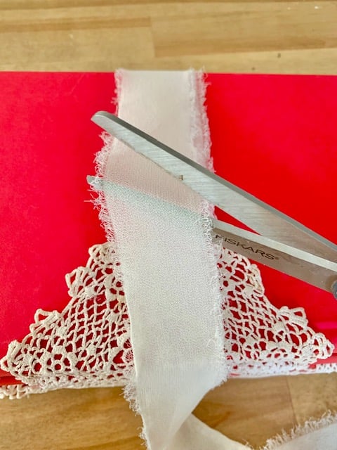 Wrapping the book stack with chiffon ribbon and using scissors to cut the ribbon once its wrapped.