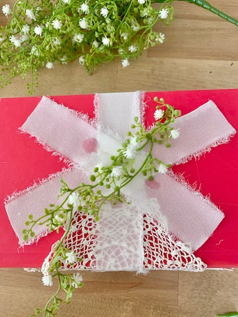 Adding a second piece of ribbon diagonally across the top and adding some greens.