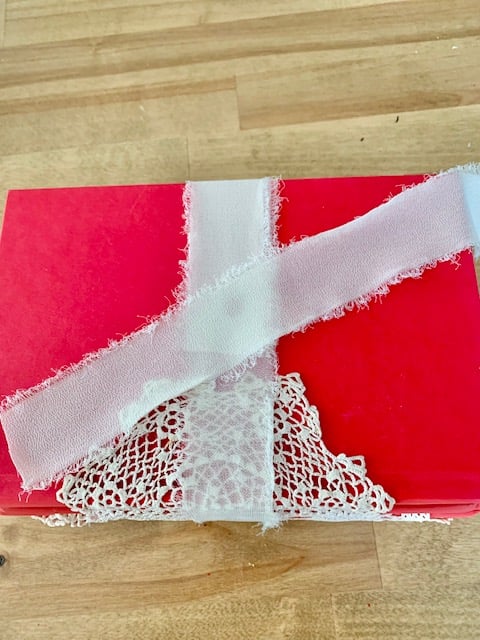 Placing a cut strip of chiffon ribbon and laying it diagonally across the top of the book.