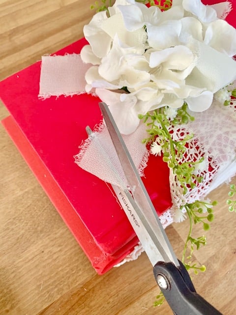 Scissors cutting the tails of the ribbon at an angle.