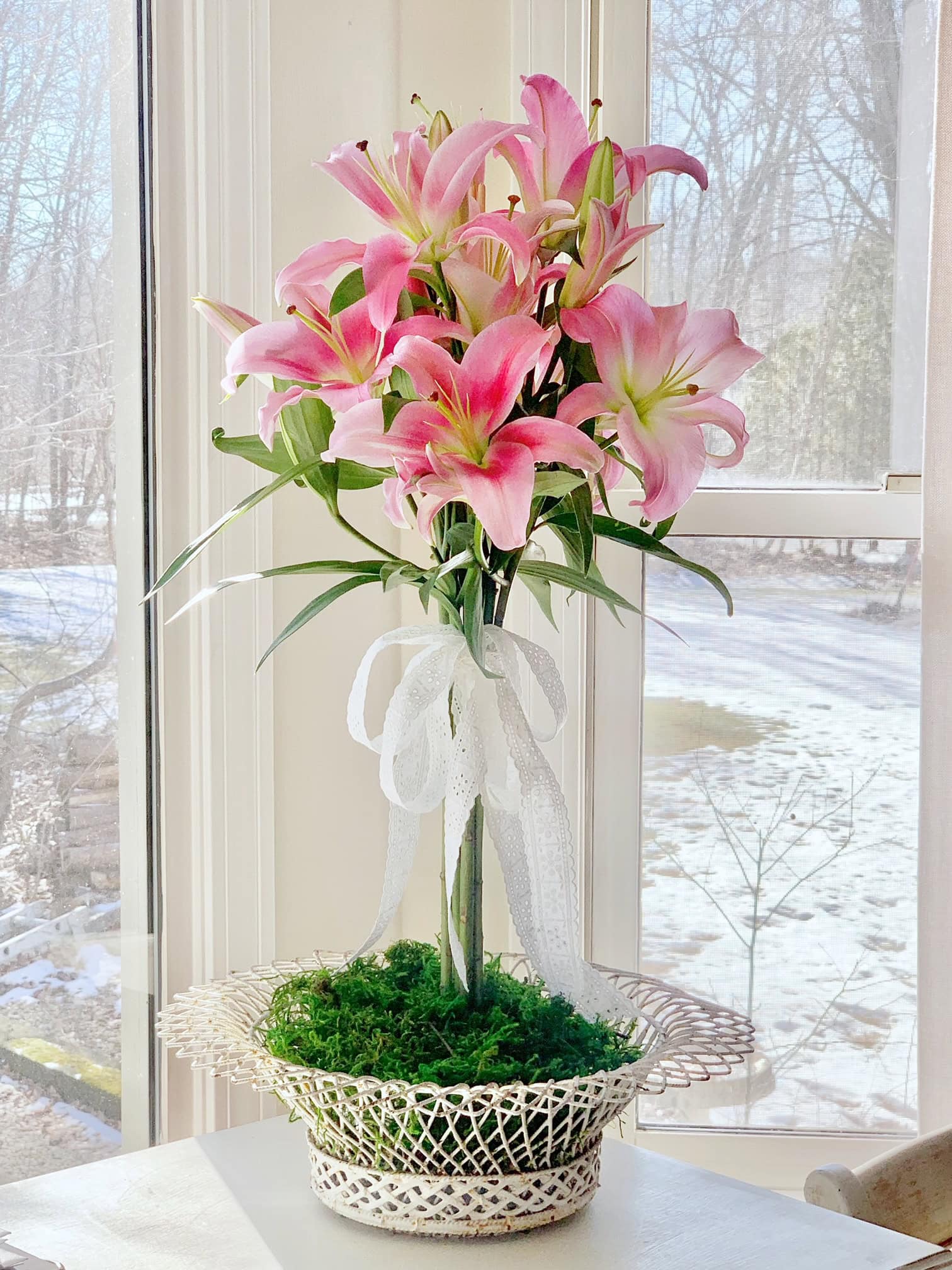 A large lily arrangement in a low shallow vintage wire basket. The lilies for a topiary. 