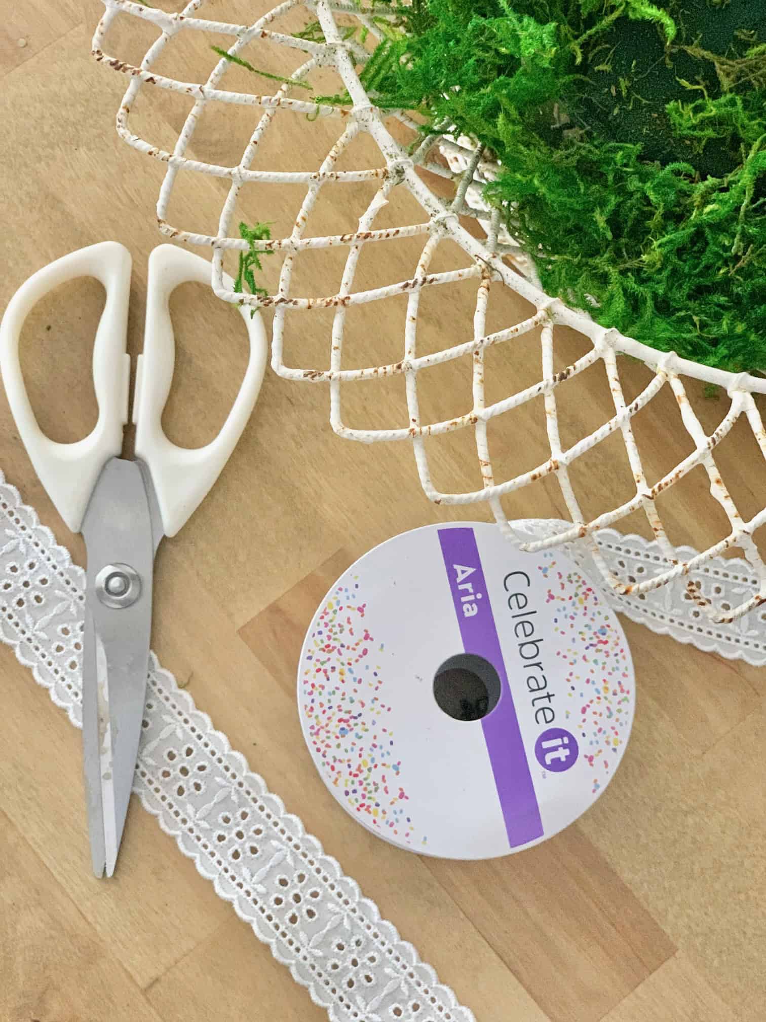 Supplies for this lily arrangement. Scissors, wired bow, moss, ribbon.