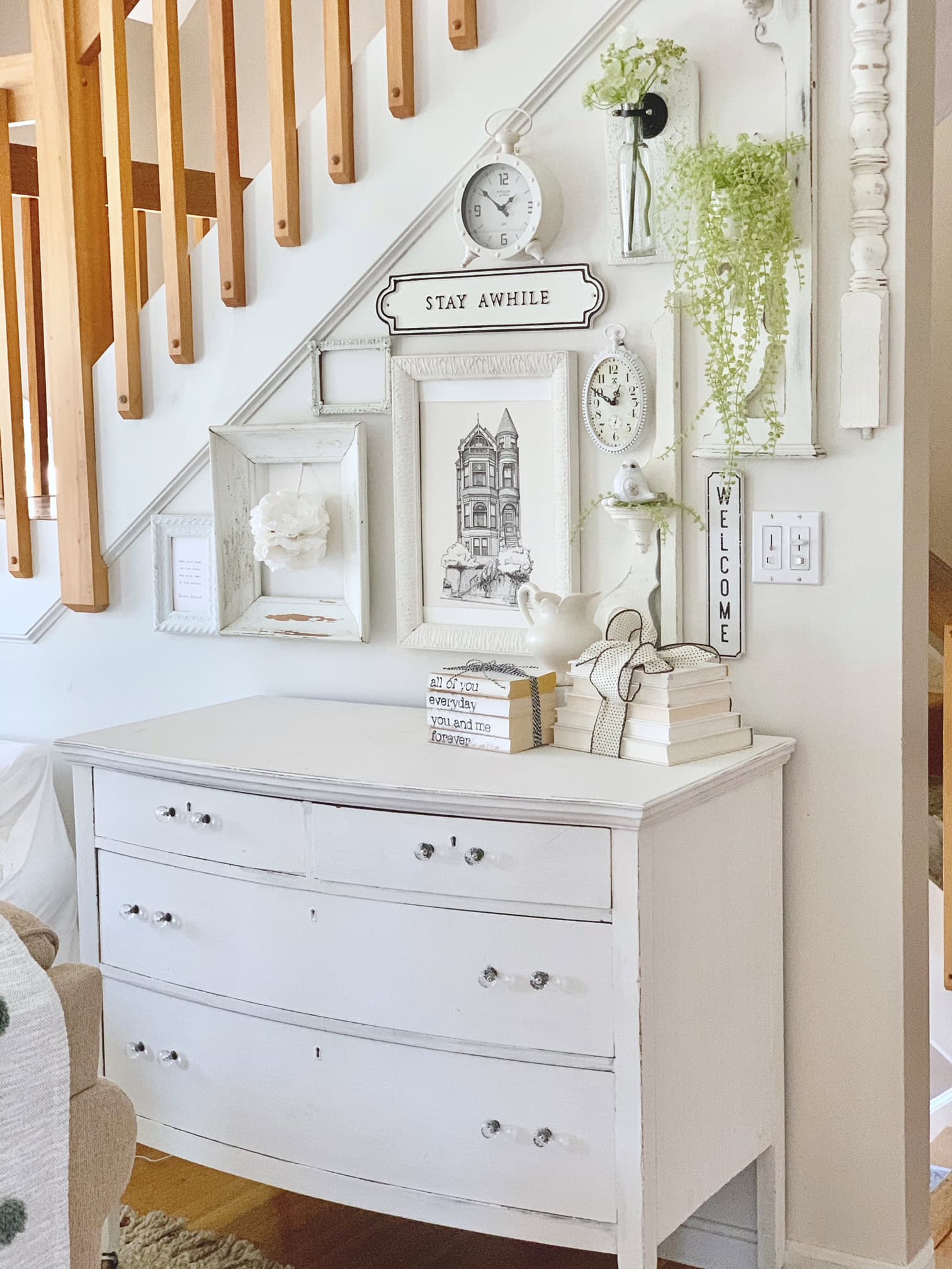 A white vintage dresser with book stacks. 