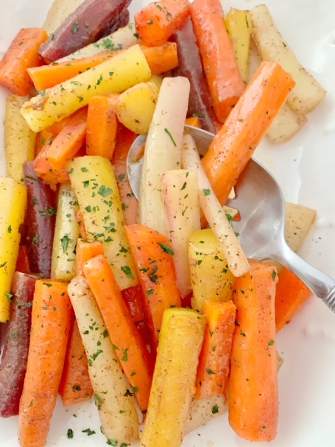 cinnamon roasted heirloom carrots in a white serving dish.