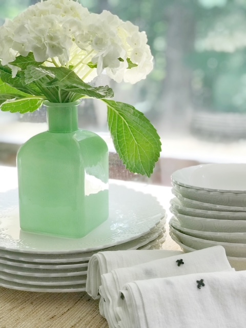 green vase holding hydrangea with plates
