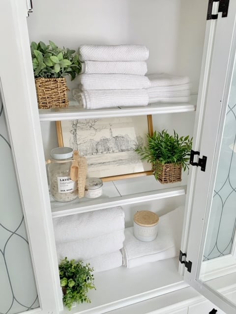 towels, faux plants and vintage prints on shelves