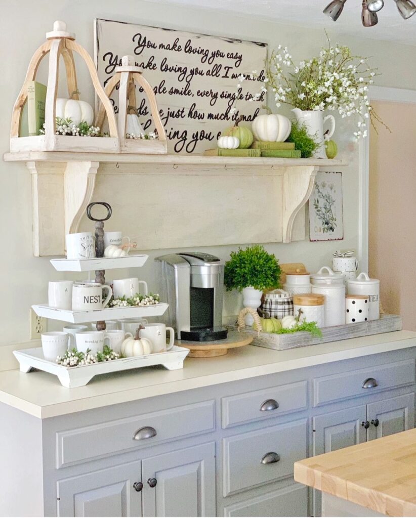 a fall coffee bar with the antique mantel turned shelf featuring green and white pumpkins, open lanterns and green vintage books.