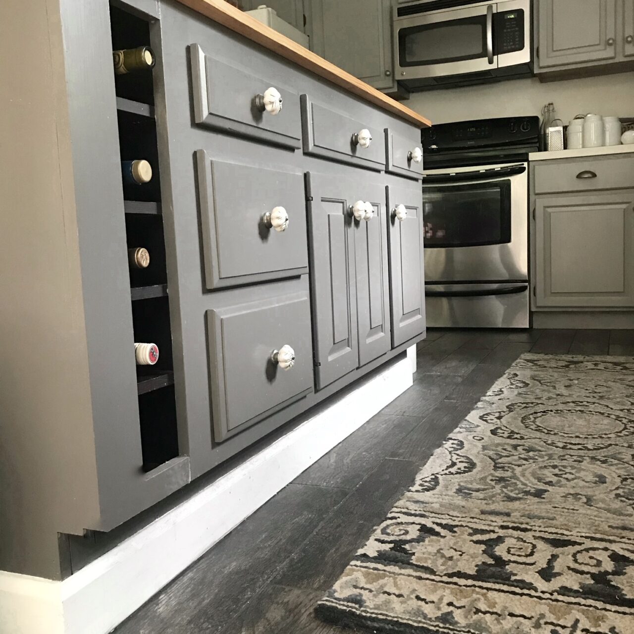 a close up of the finished kitchen island in dark gray with butcher block top.