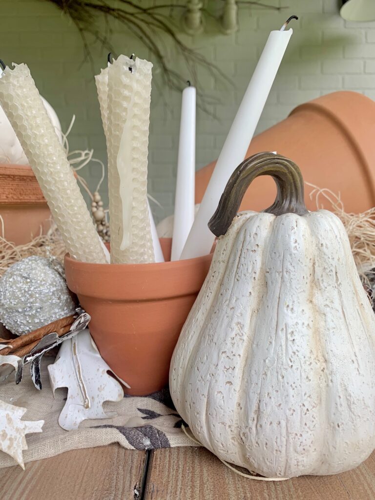 white faux gourd with a clay pot with taper candles in it. 