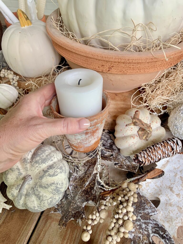 small clay pot with white pillar candle.