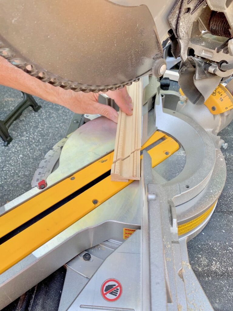 a miter saw cutting the the trim pieces at 45 degree angles for the corners
