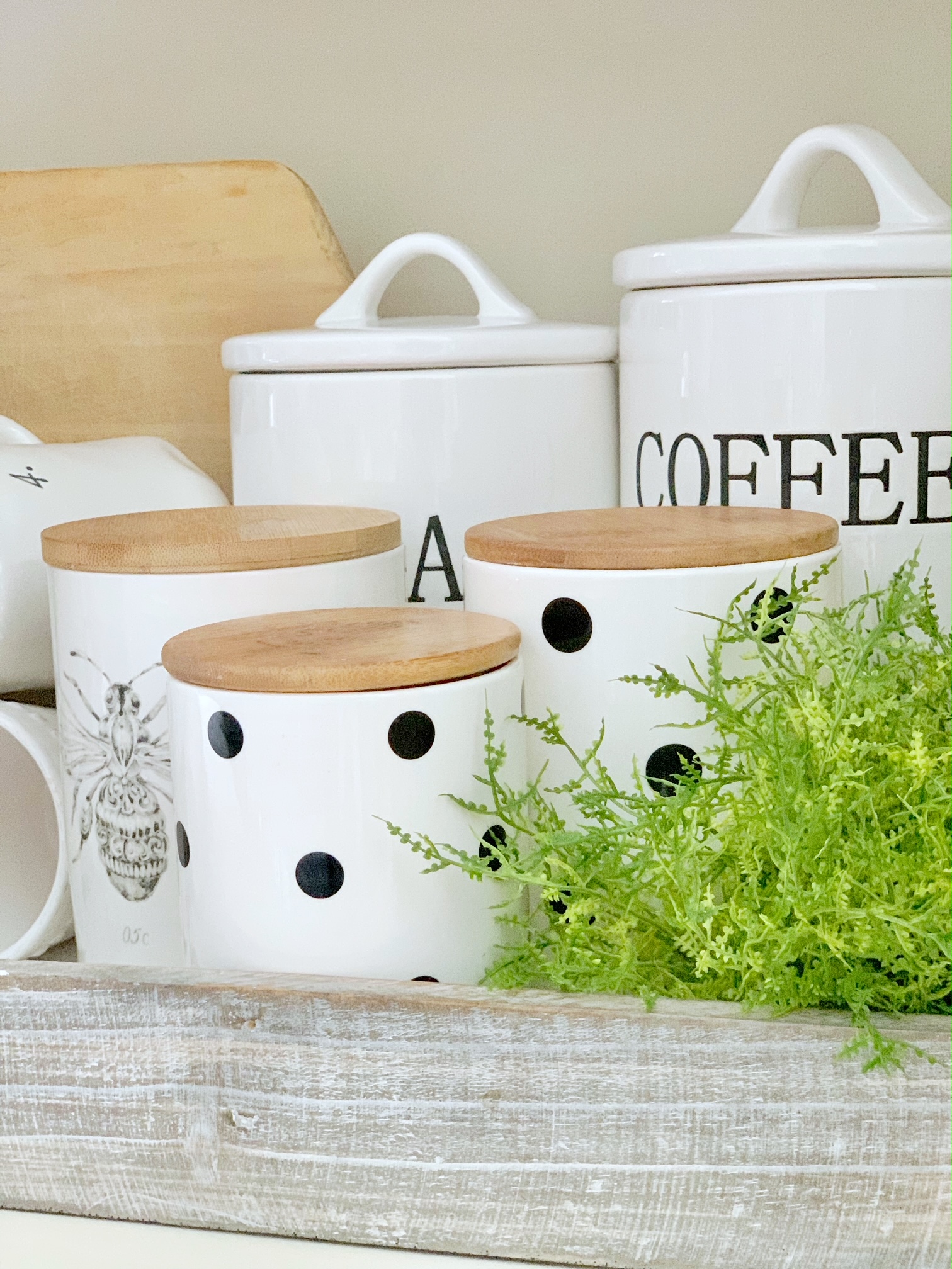 White canisters with greens.