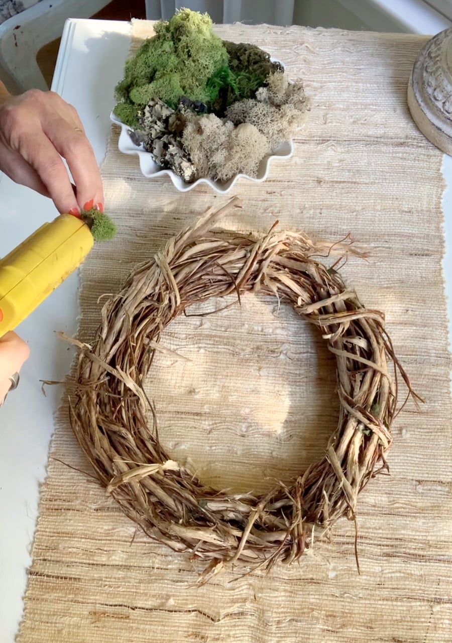 Adding moss to a Grapevine wreath.