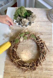 gluing dried moss to the grapevine wreath.