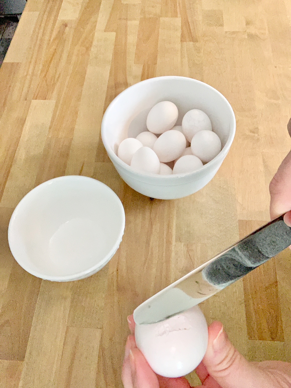 Removing the top of an eggshell with a knife.
