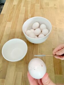 tapping egg with knife to remove the top.