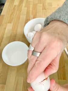 pushing thumb into egg to lift top off.