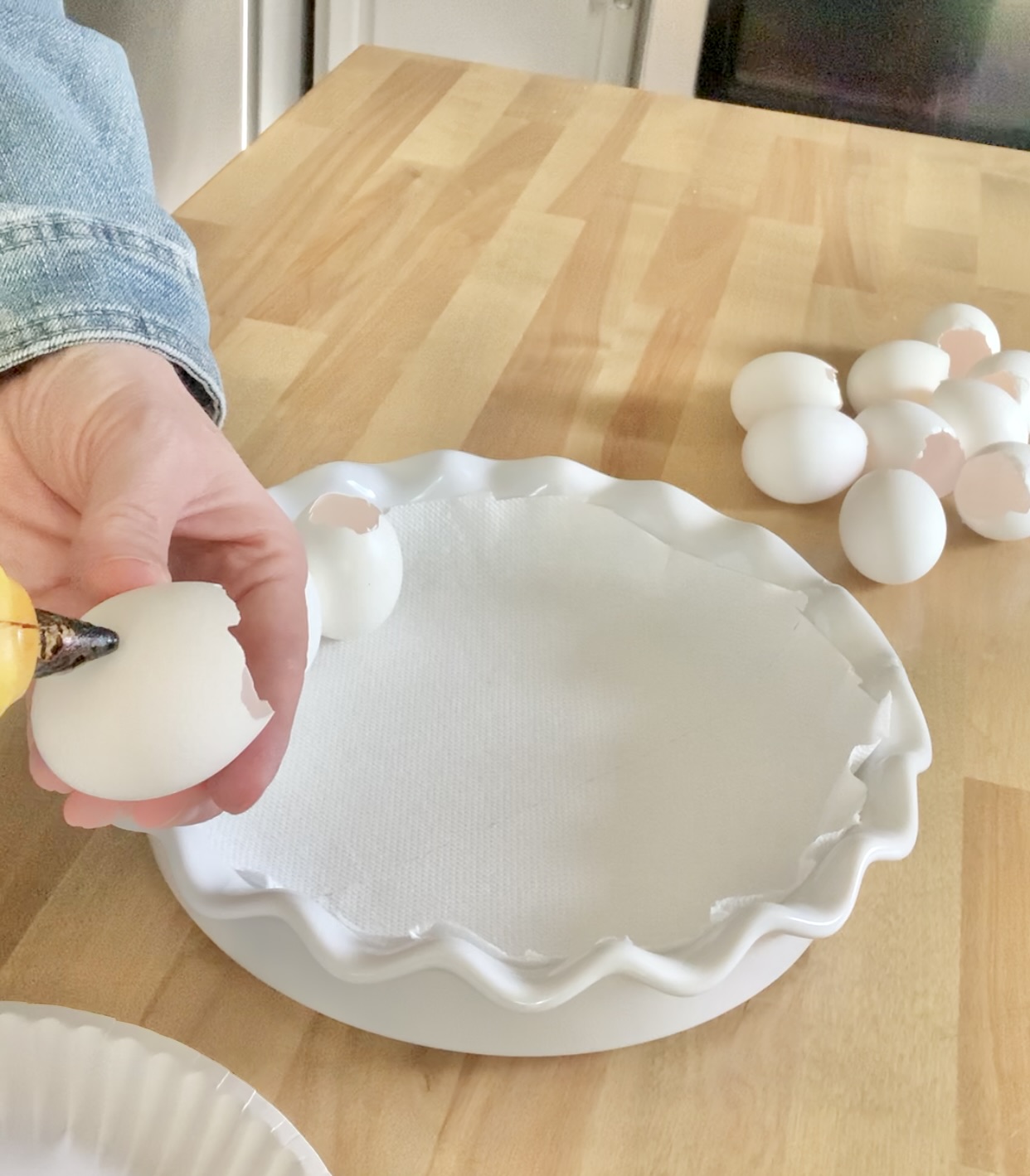 Adding a dab of hot glue to the side of an empty egg and forming ring in the pie plate.