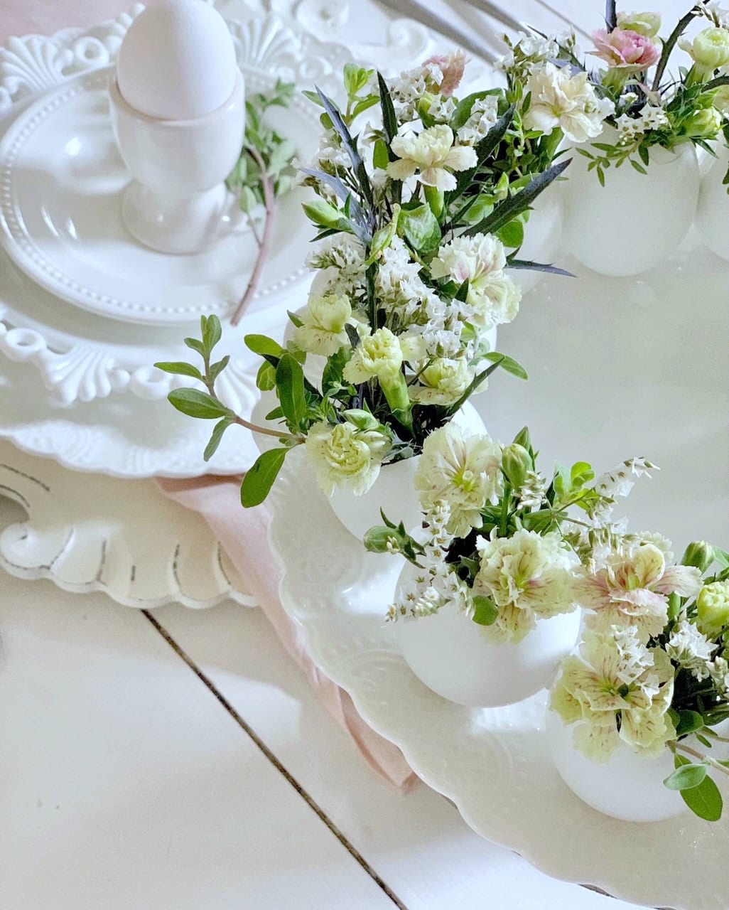 A ring of white eggs that have been emptied with fresh flowers in each egg. 