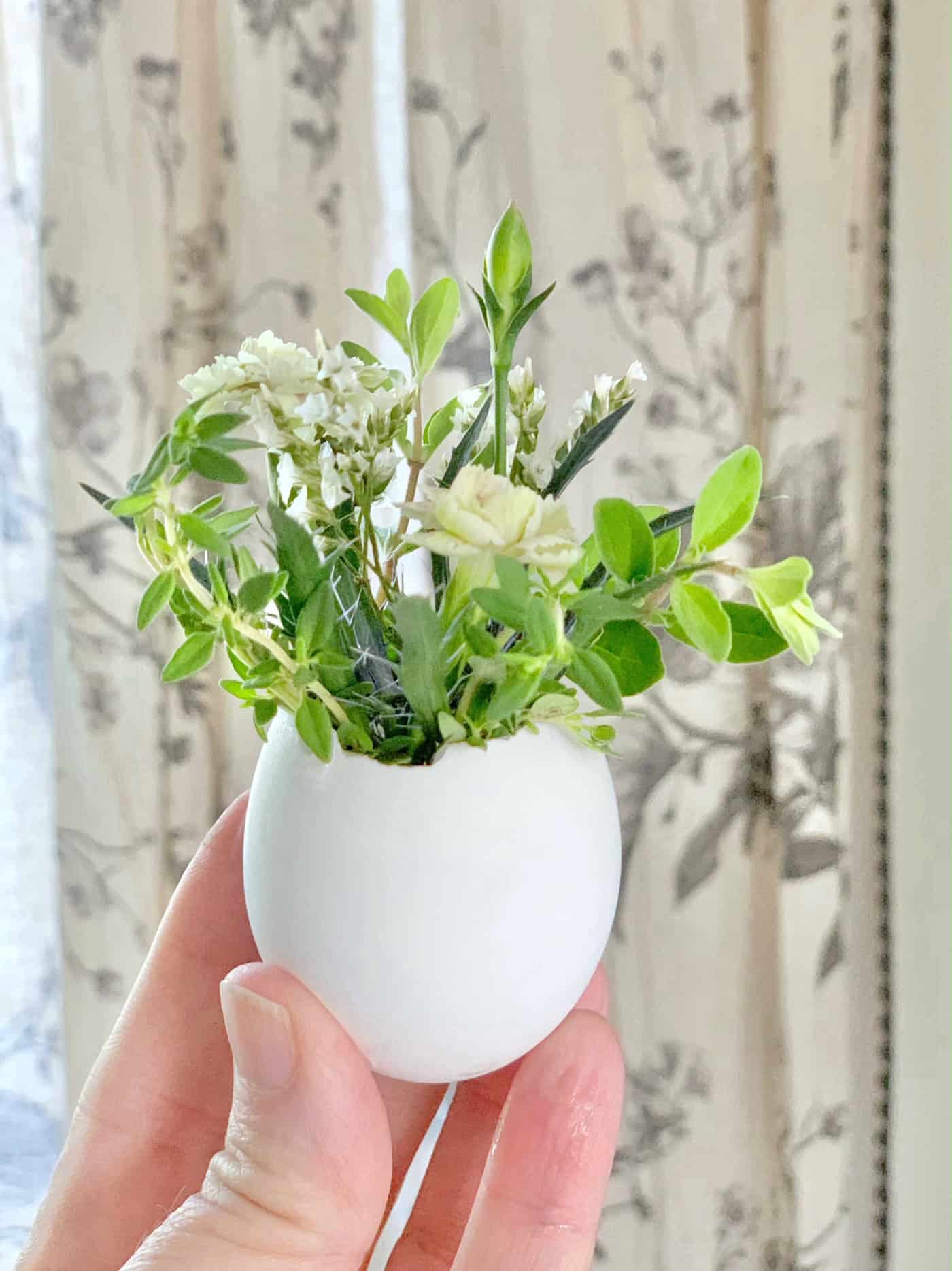 Single white egg with fresh flowers added to it. 