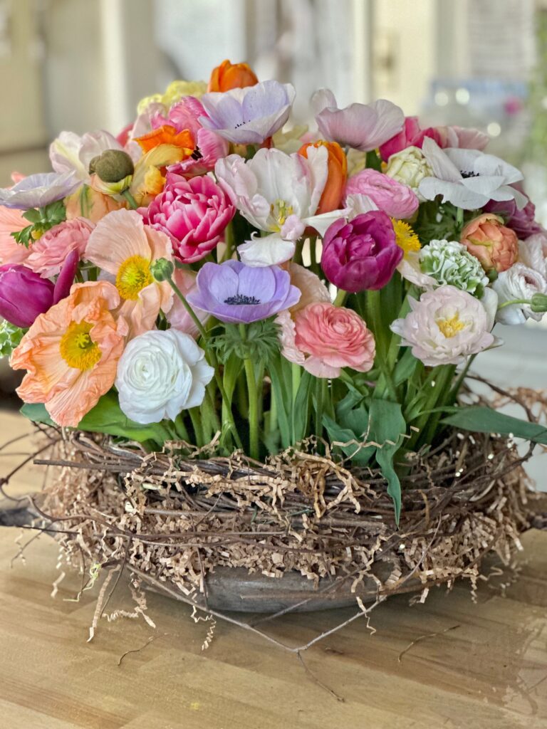a tulip bouquet using wet floral foam. The tulips are very colorful and are sitting in a birds nest container. 