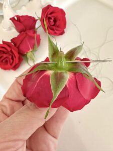 piercing the needle through the rose head.