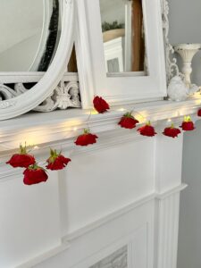 hanging the garland on a white decorated mantel.