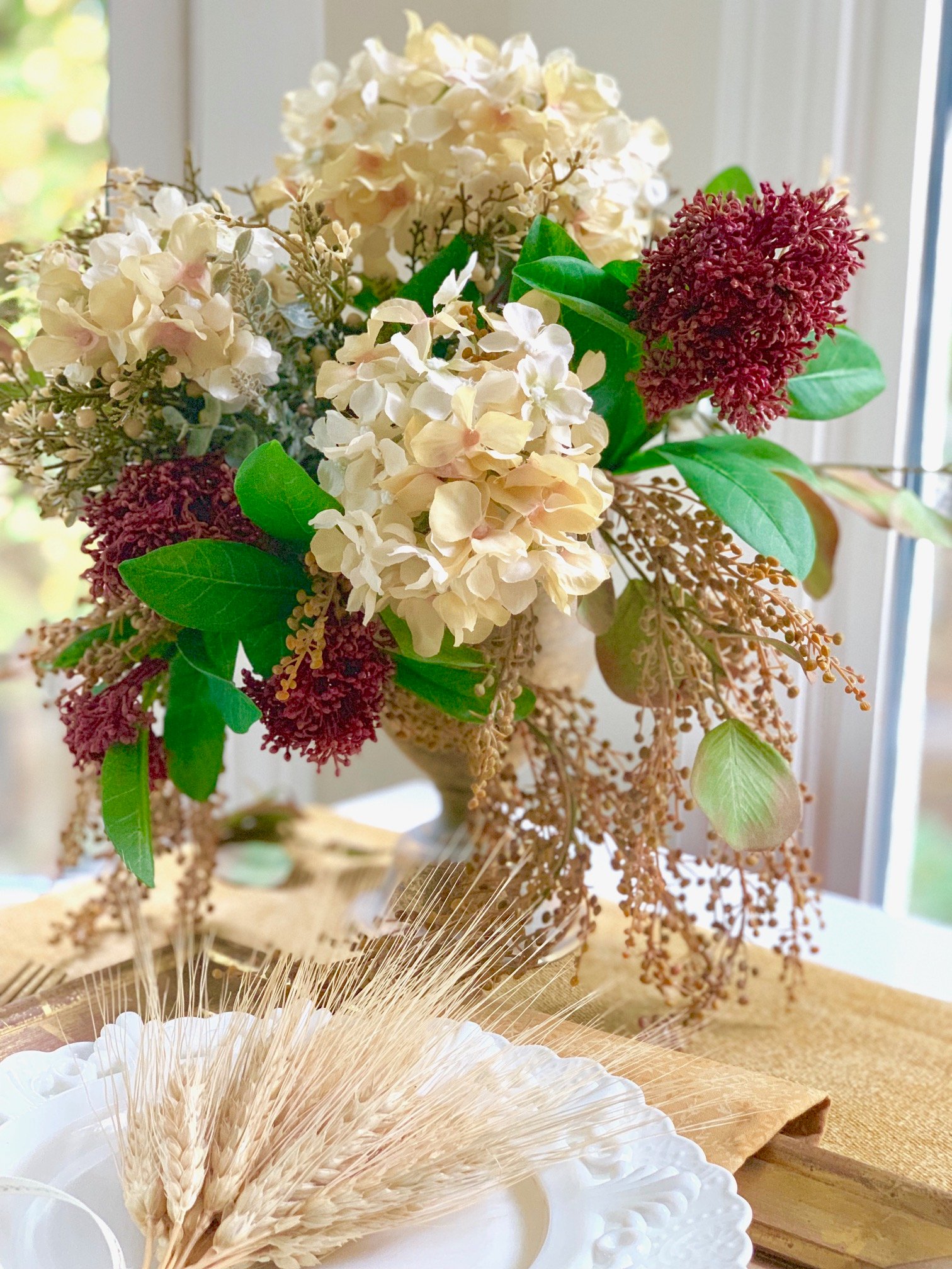 Faux fall flowers in a gold vase that has dry flower foam.