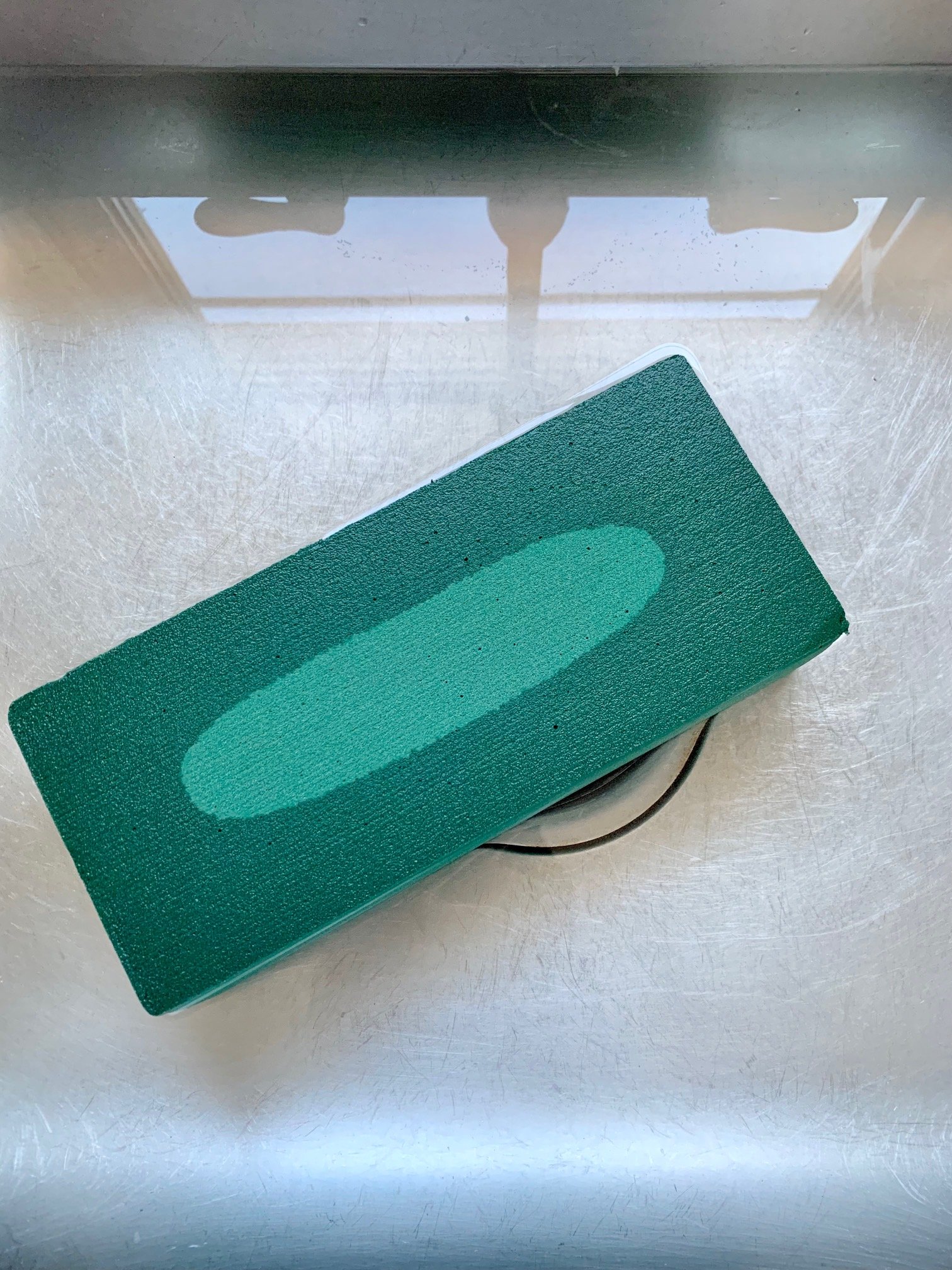 A block of wet floral foam soaking in a kitchen sink.