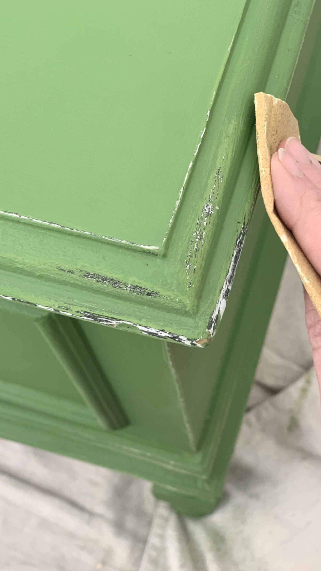sanding a green chest with sand paper